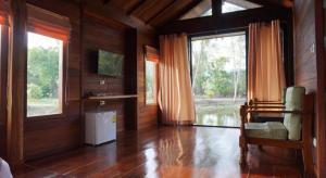 a living room with wooden walls and a large window at Hotel Golf 19 in Ban Hua Khao