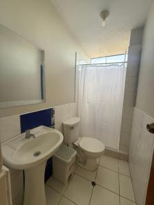 a white bathroom with a sink and a toilet at Oasis in Tacna
