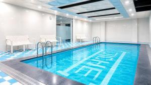 a large swimming pool with blue water in a room at Plott Archive Jeju in Jeju