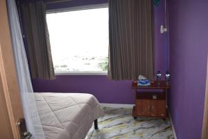 a bedroom with purple walls and a bed and a window at Puri Ma'u Beach & Bungalows in Boba