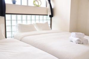 two white beds in a bedroom with towels on them at サンヒルズマンション in Tosu