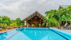 a villa with a swimming pool in front of a house at Lion Wood Treehouse in Talkote