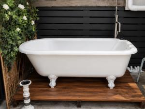 a white bath tub sitting on a wooden deck at Bach By The Beach in Mount Maunganui +32 photos