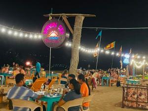 a group of people sitting at tables on the beach at night at Vitamin sea beach cabana in Nilaveli