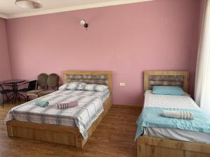 two beds in a room with a pink wall at Maiko's House in Batumi