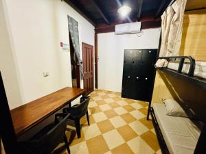 a room with a desk and a table and chairs at Wood Wood Hostel in Vientiane