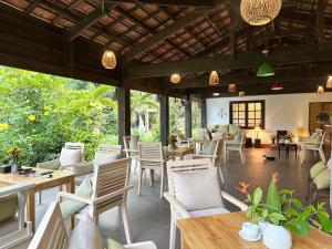 a restaurant with white chairs and tables and windows at MK Hill resort Phu Quoc in Phú Quốc