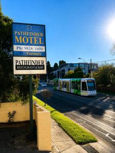 a sign for a hotel next to a street with a train at Pathfinder Motel in Melbourne