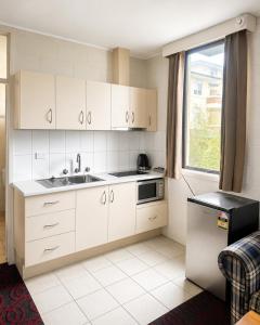 a kitchen with white cabinets and a sink and a window at Pathfinder Motel in Melbourne