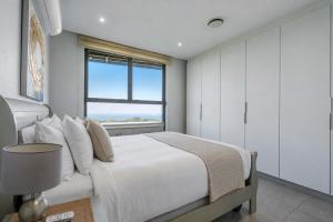 a bedroom with a large white bed with a window at Ocean Vista Pebble Beach in Umhlanga