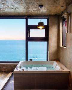 a large bath tub in a room with a large window at Samcheok Laon Spa Pension in Samcheok