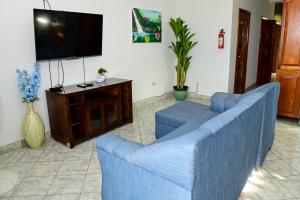 a living room with a blue couch and a tv at EV's Place in San Ignacio