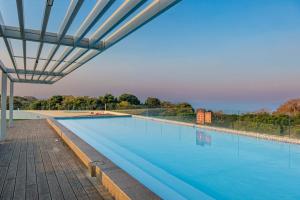 a large swimming pool with a canopy over it at Ocean Vista Pebble Beach in Umhlanga +3 photos