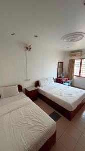 a bedroom with two beds and a desk and a window at Hotel CY in Sungai Besar