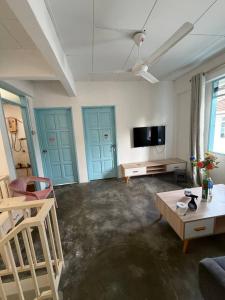 a living room with blue doors and a flat screen tv at Stellas house in Langkawi Islands
