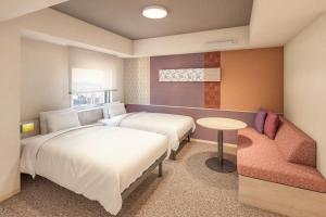 a hotel room with two beds and a chair at たびのホテルlit豊川 in Toyokawa
