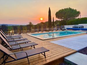 a pool with chairs and a sunset in the background at Résidence Le Petit Duc in Carcassonne