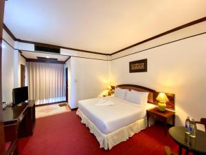 a bedroom with a bed and a desk and a television at Crystal Hotel Krabi in Krabi