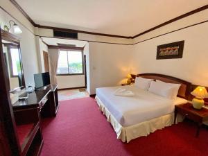 a hotel room with a bed and a desk and a television at Crystal Hotel Krabi in Krabi