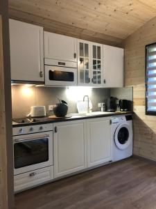 a kitchen with white cabinets and a washer and dryer at Fanjeaux Aude Le Chalet in Fanjeaux