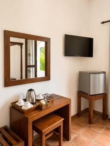 a room with a table with a mirror and a television at River Bay Hotel in Pillagoda