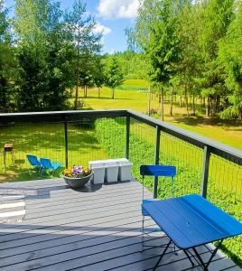 a deck with two blue chairs and a bowl of flowers at iNKiLAS KLIUKAI in Bijutiškis