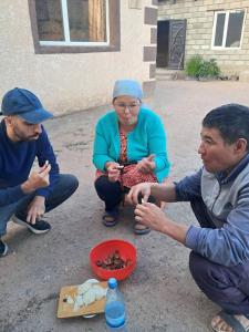 a group of people sitting around a bowl of food at Kamas Guesthouse in Kyzart +50 photos
