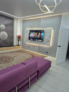 a living room with a purple bed and a flat screen tv at На Желтоксан in Taldykorgan