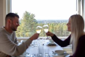 a man and woman holding up wine glasses at a table at Santasport Apartment Hotel in Rovaniemi +25 photos