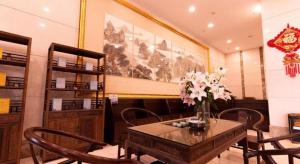 a dining room with a table with a vase of flowers on it at Bashan Hotel in Xiamen