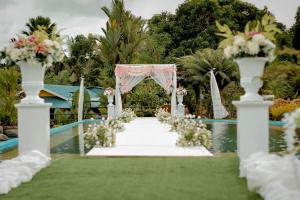 a wedding aisle with a white arch and flowers at Churinga Eco Resort in Tigaon +5 photos