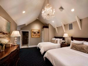 a bedroom with two beds and a chandelier at The Federal Pointe Inn Gettysburg, an Ascend Collection Hotel in Gettysburg