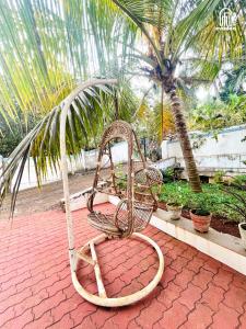 a rattan chair sitting on a patio with a palm tree at Aamra Ghar by evaddo stays in Mandrem