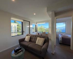 a living room with a couch and a bed and windows at 110 Hampden Apartments in Hobart