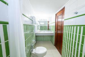 a green and white bathroom with a toilet and a sink at Hotel Faranda Express Soloy and Casino, a member of Radisson Individuals in Panama City