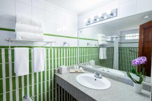 a green and white bathroom with a sink and a mirror at Hotel Faranda Express Soloy and Casino, a member of Radisson Individuals in Panama City