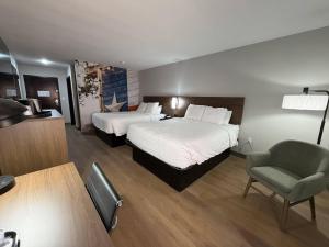 a hotel room with two beds and a chair at Clarion Pointe Addison - Dallas North in Addison +1 photo