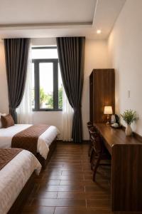 a hotel room with two beds and a desk at Hotel Gia Hưng in Bảo Lộc