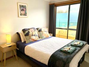 a bedroom with a large bed with a window at Wintersun Holiday Cottages in Emu Bay