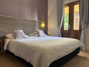 a bedroom with a large white bed with a window at Le djebel in Cilaos