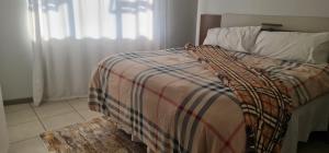 a bed with a striped comforter in a bedroom at Northview APARTMENTS SELF CATERING in Pretoria