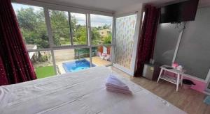 a bedroom with a white bed and a large window at Baan Gon Chompu in Suan Phung