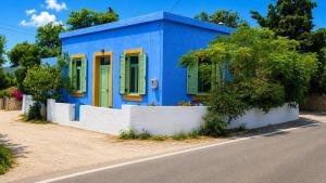 a blue house with green shutters on a street at The Blue - Kythira in Kondoliánika