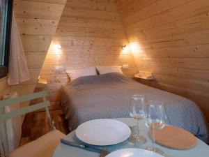 a room with a bed with two plates and wine glasses at La cabane en A 