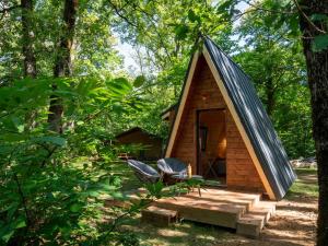 a tiny house in the woods with a porch and a table and chairs at La cabane en A 