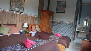 two beds in a room with pink pillows on them at Dewa Bungalows, A Balinese House and Art Gallery in Ubud