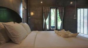 a bedroom with a bed with white pillows and windows at V Valley Resort in Satun +83 photos