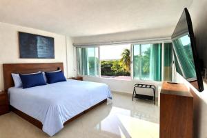 a bedroom with a bed with blue pillows and a window at Brisas Shores Beachfront connecting apartments, Cancun Hotel Zone in Cancún