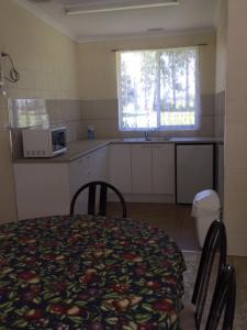 a kitchen with a table and chairs and a kitchen with a microwave at Snowy River Lodge Motel in Orbost