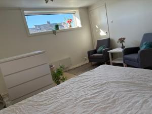 a bedroom with a bed and two chairs and a window at Northern Suite in Tromsø